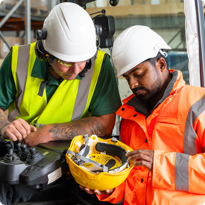 Centurion Safety. Two workers in Hi-Viz inspecting a safety helmet
